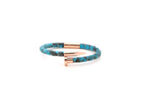 A bracelet with aqua-blue python leather and rose gold plated nail head.