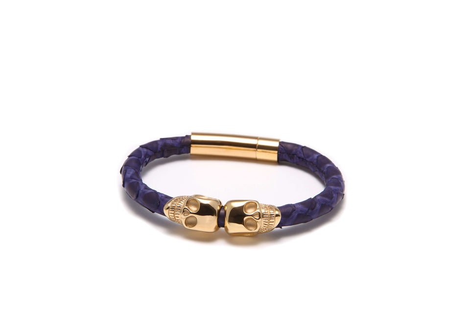 A blue leather bracelet with gold-plated skull-shaped accents and gold-plated clasps.