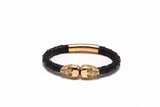 Black leather bracelet with gold skull clasp on a white background