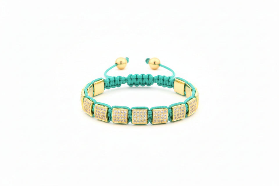 Green braided bracelet with gold square beads on a white background
