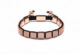 Rose gold bracelet with black cord on a white background