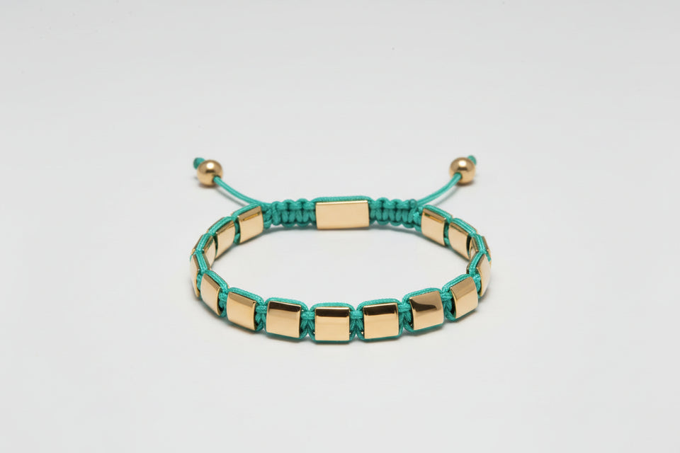 Bracelet with gold and green beads on a light gray background