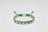 Bracelet with gold and green beads on a light gray background
